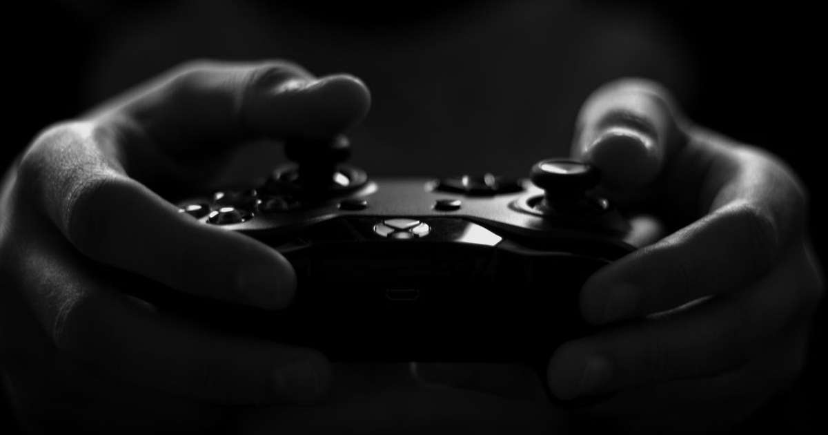 Hands holding a game controller in the dark