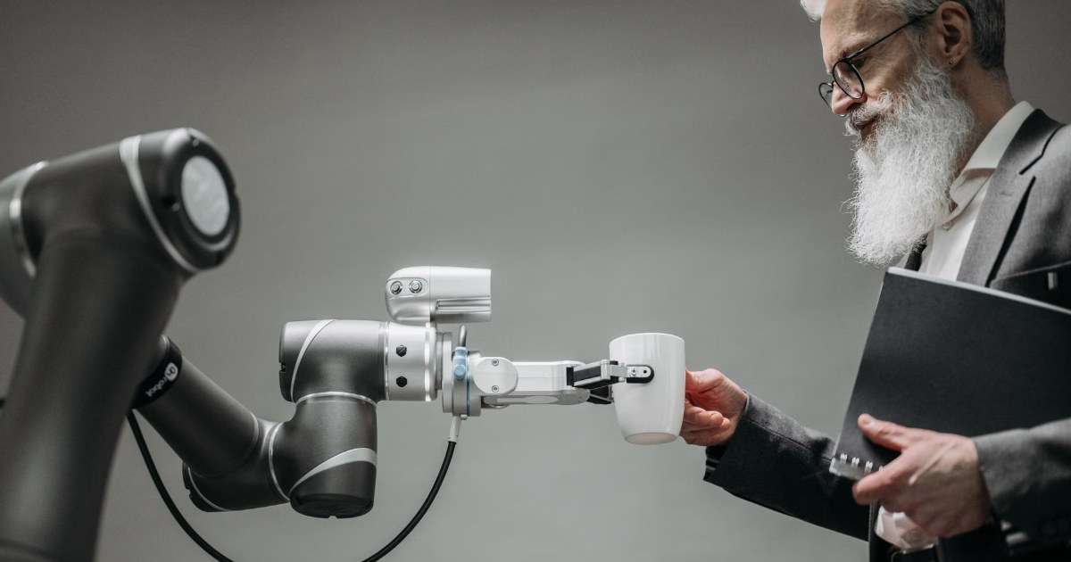 A robot arm handing a cup to an office worker